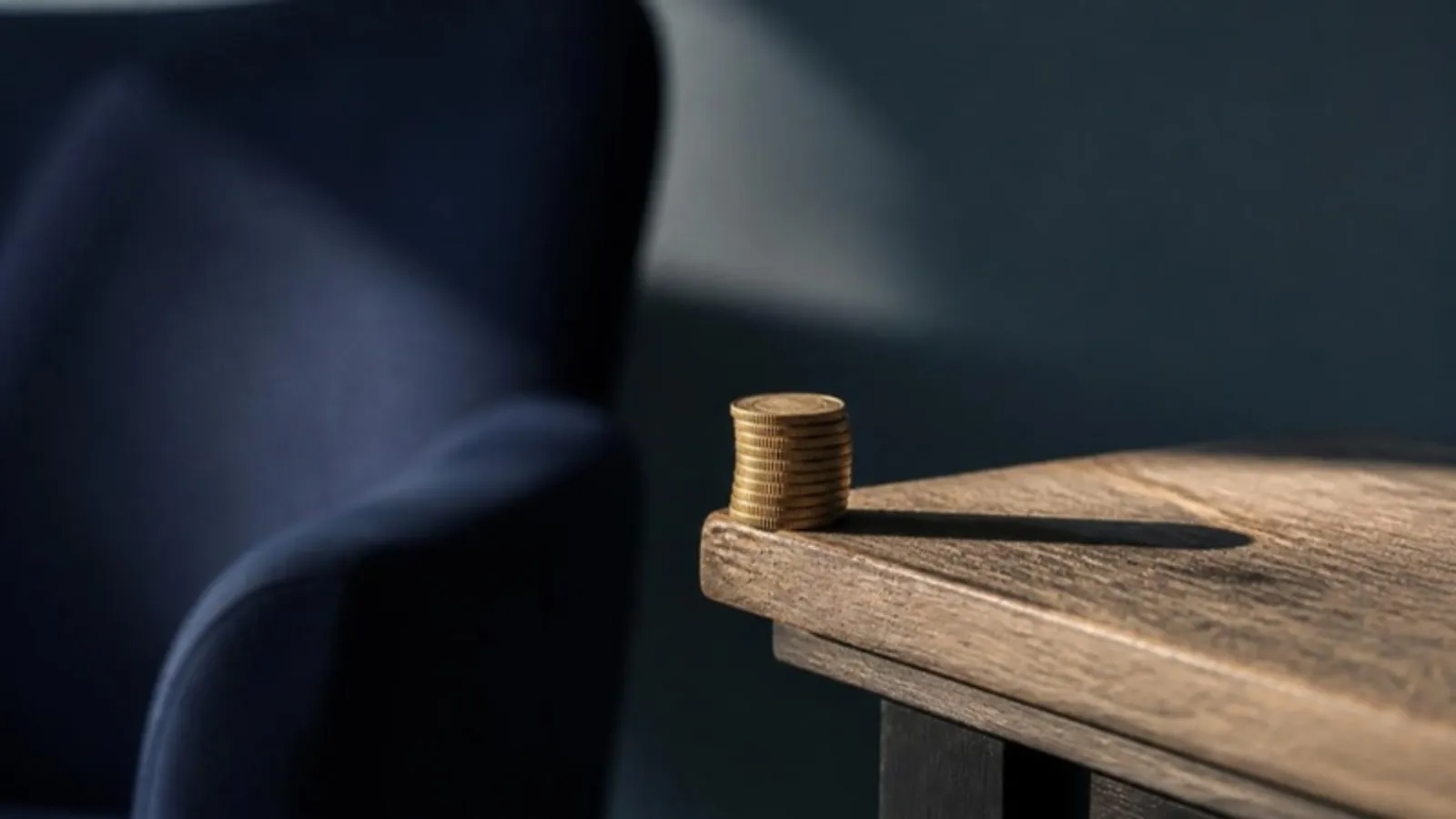 Goldmünzen sind riskant am Rand eines Holztisches gestapelt