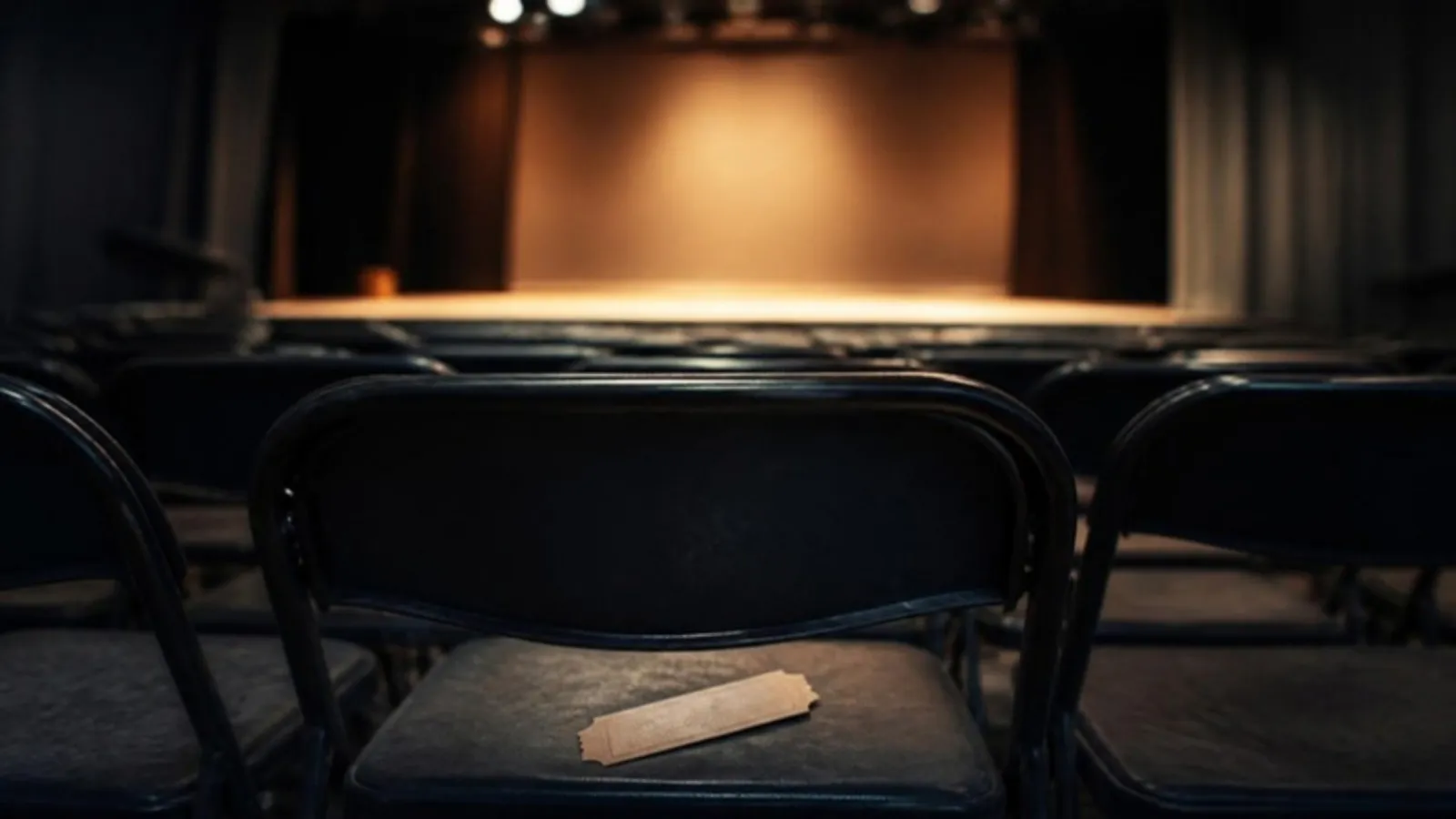 Leere Stuhlreihen vor einer Bühne mit Ticket auf dem vorderen Sitz
